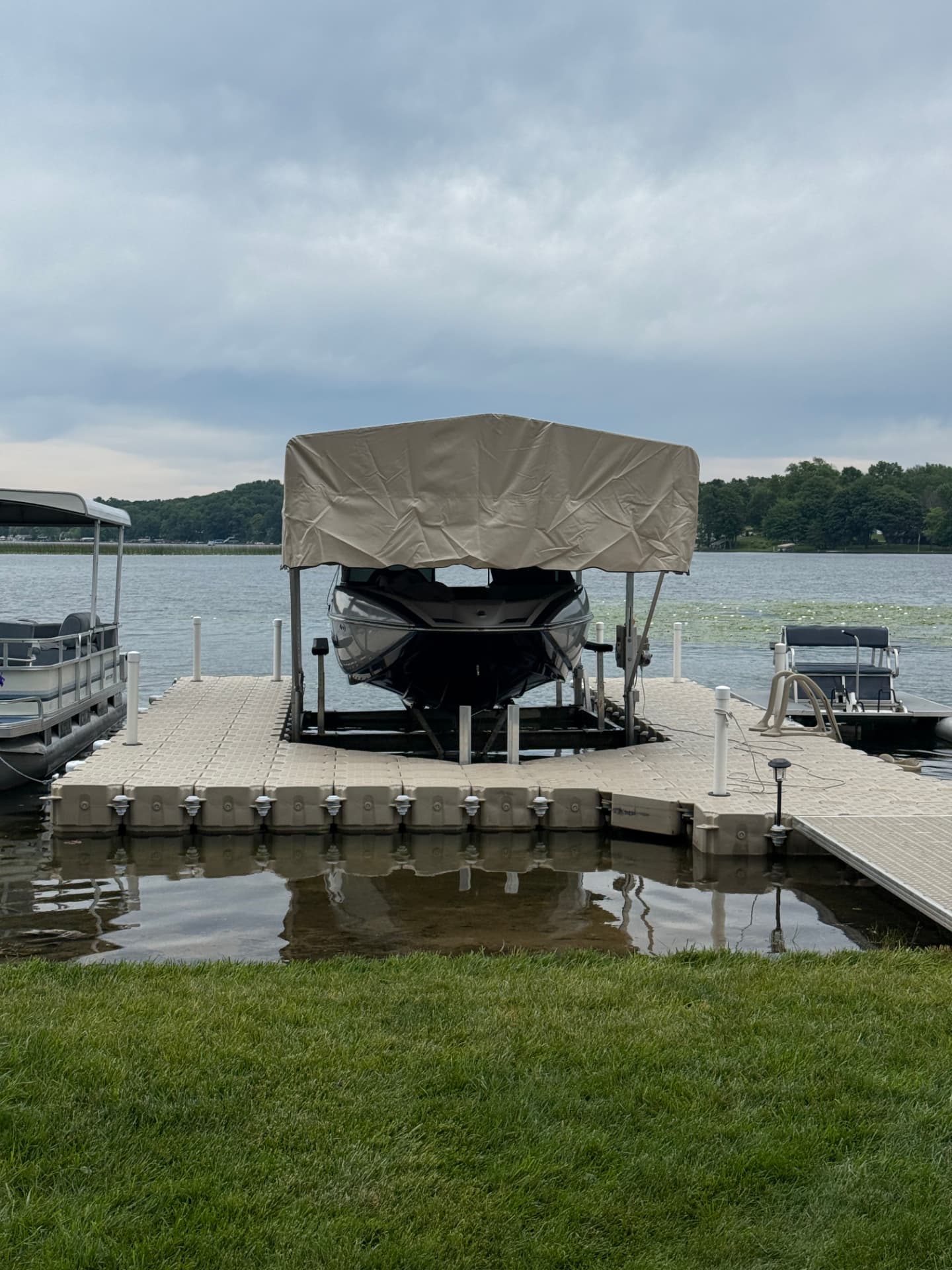 Boat resting on a canopied lift surrounded by a floating dock on a Michigan lake