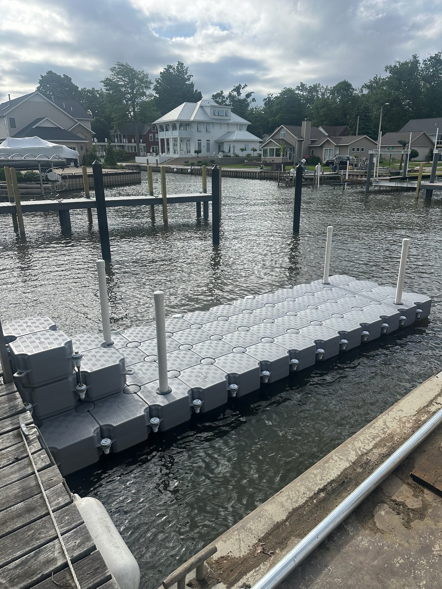 Grey CanDock walkway installed along a narrow residential shoreline with upright anchoring posts