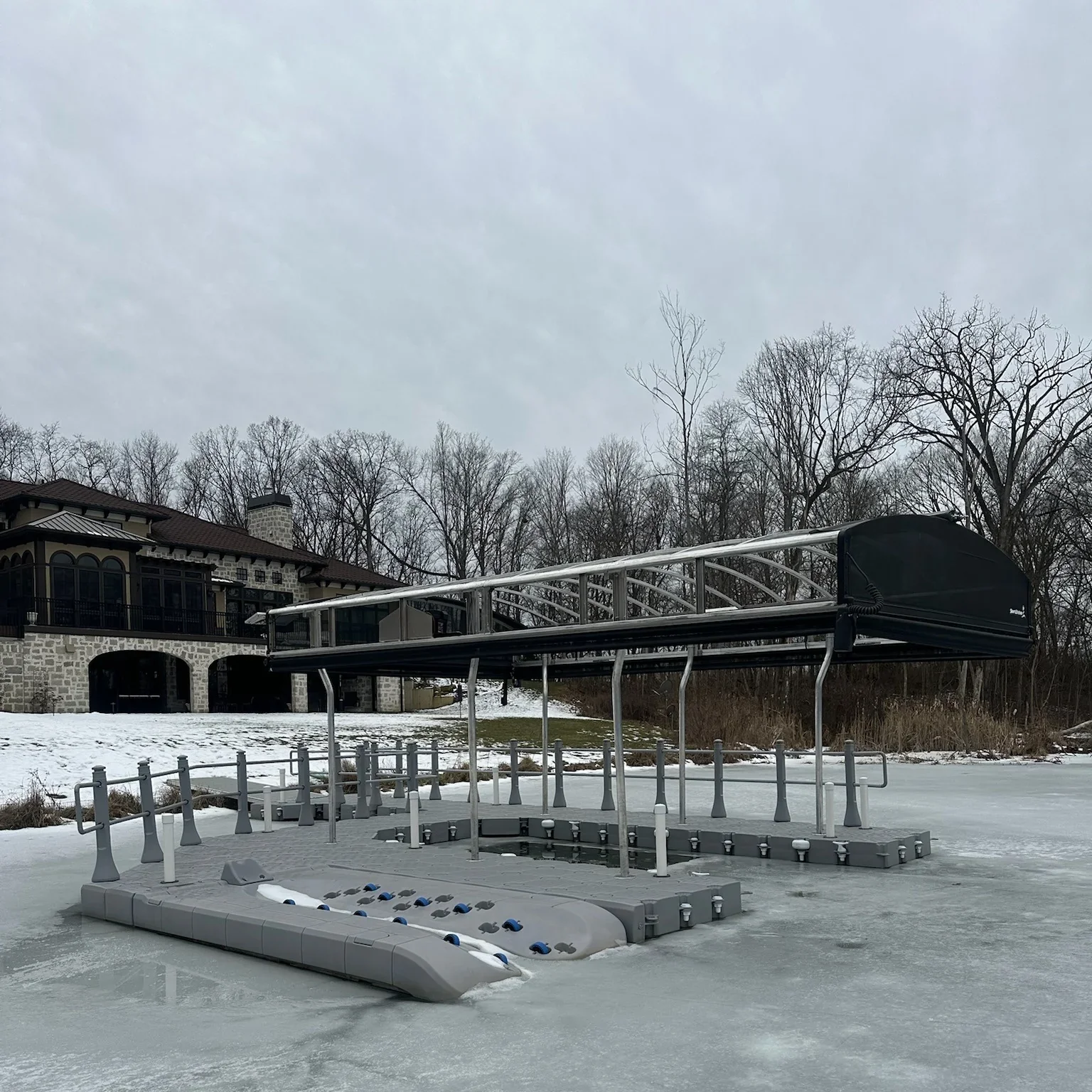 CanDock modular floating dock left in the water through winter ice with a ShoreStation canopy