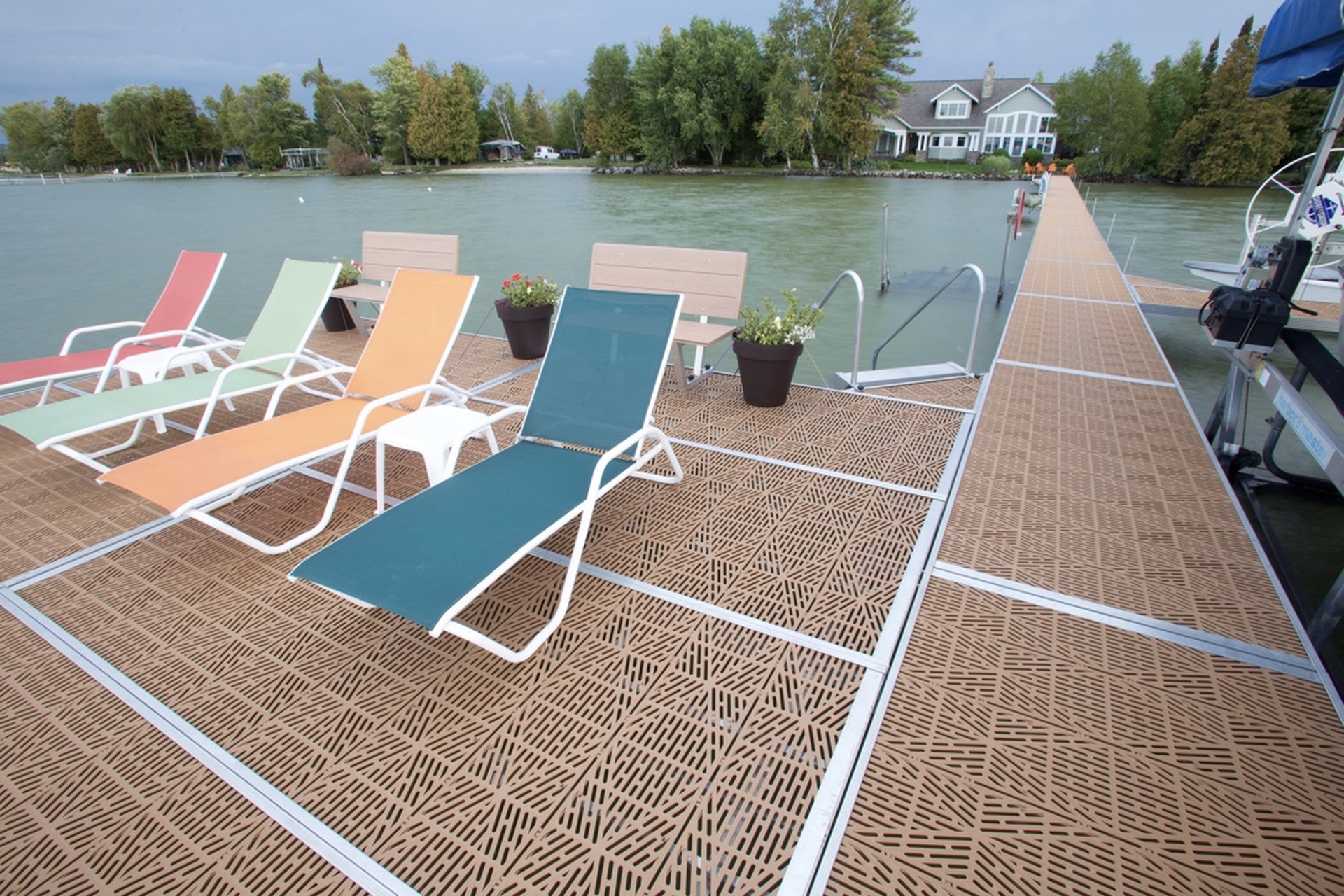 Twin Bay dock with tan flow-through decking, lounge chairs, benches and potted flowers beside a long walkway