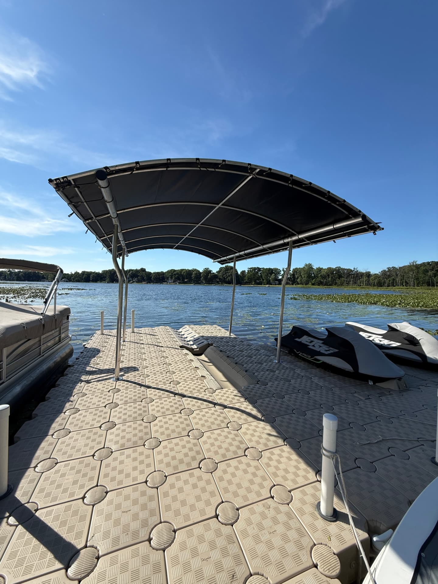 Two personal watercraft stored on drive-on CanDock sections beneath a shade canopy