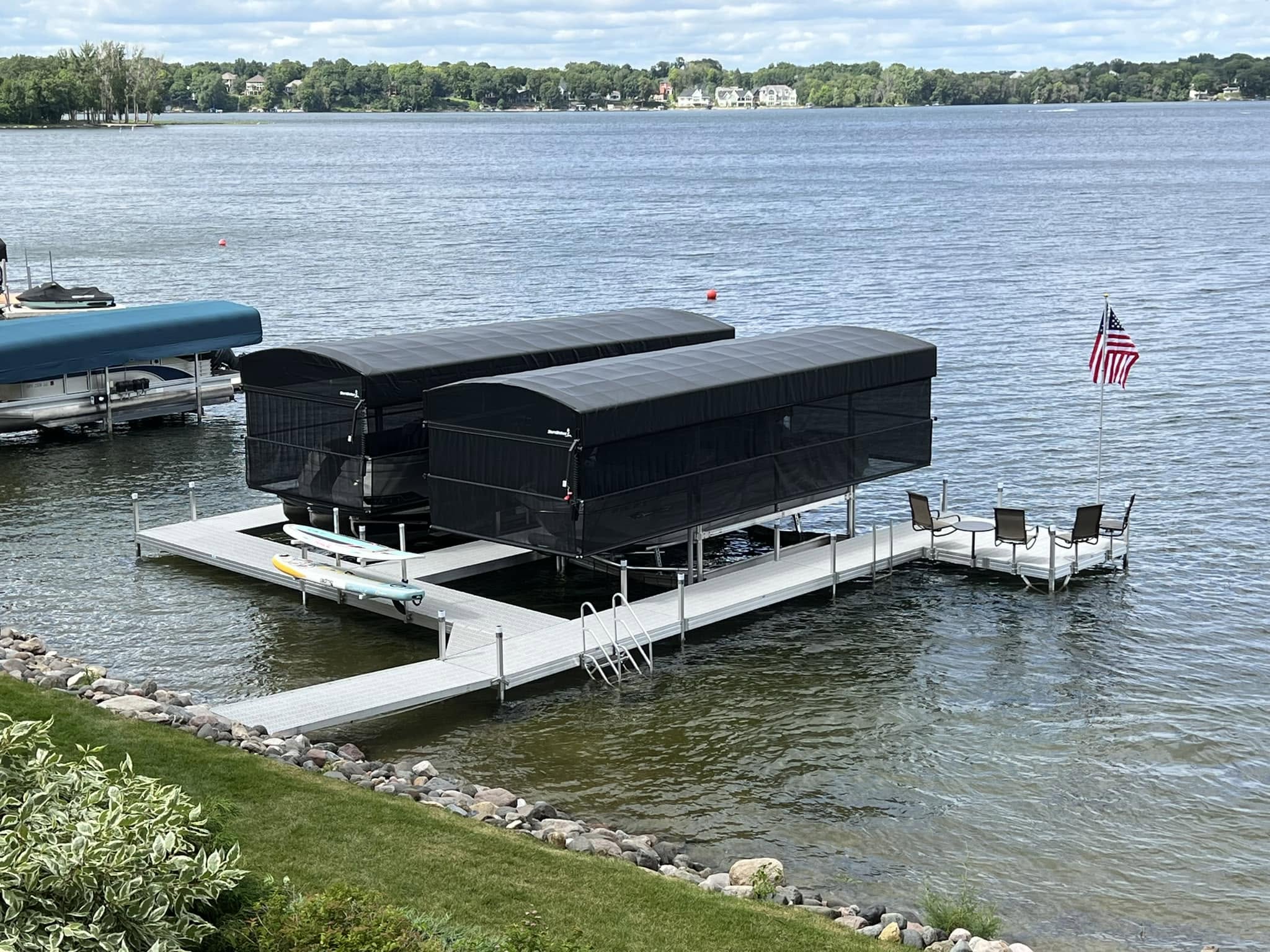 Two ShoreStation boat lifts with black protective canopy enclosures beside an aluminum lake dock