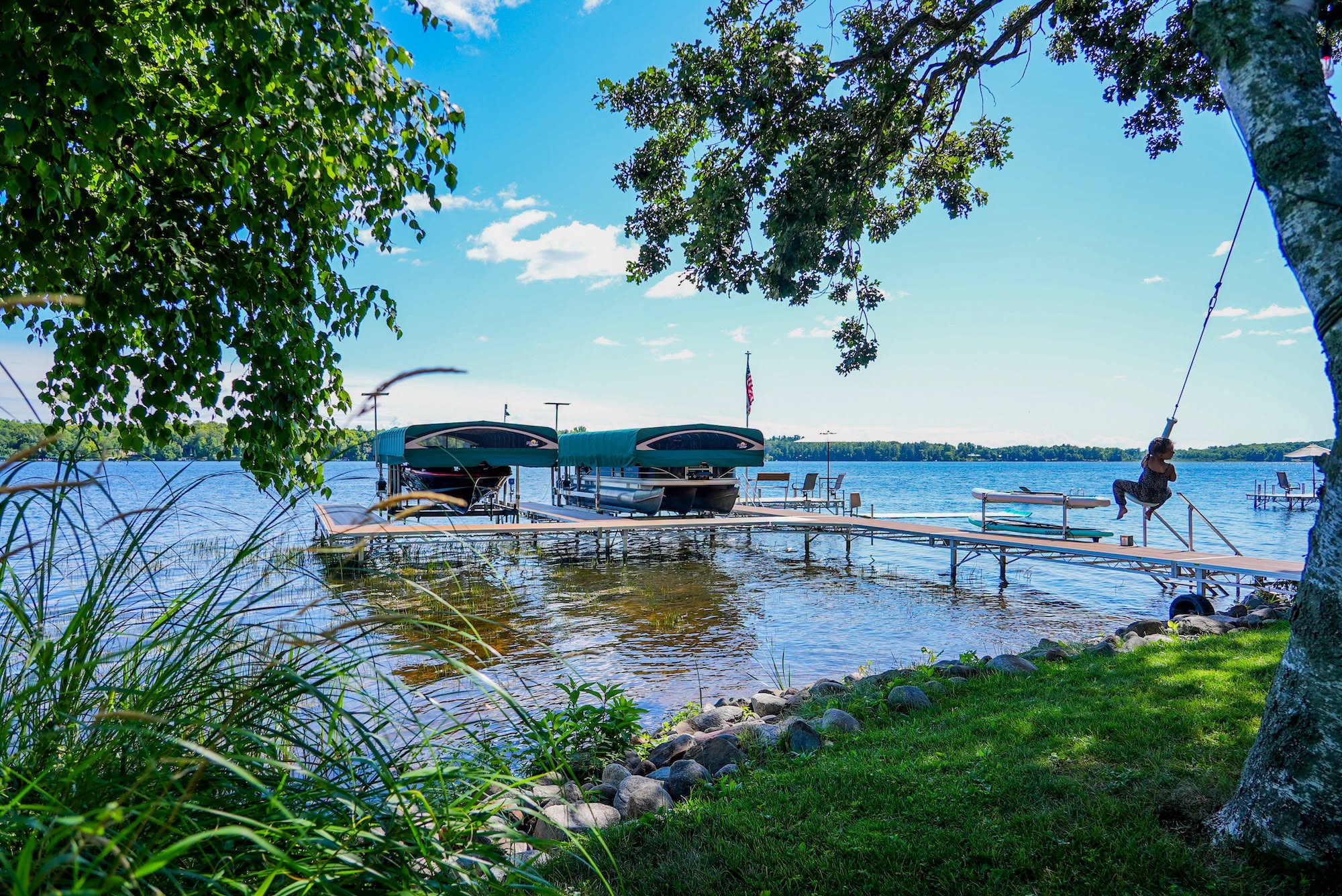 Michigan lakefront with covered boat lifts and an aluminum dock seen from a shaded backyard