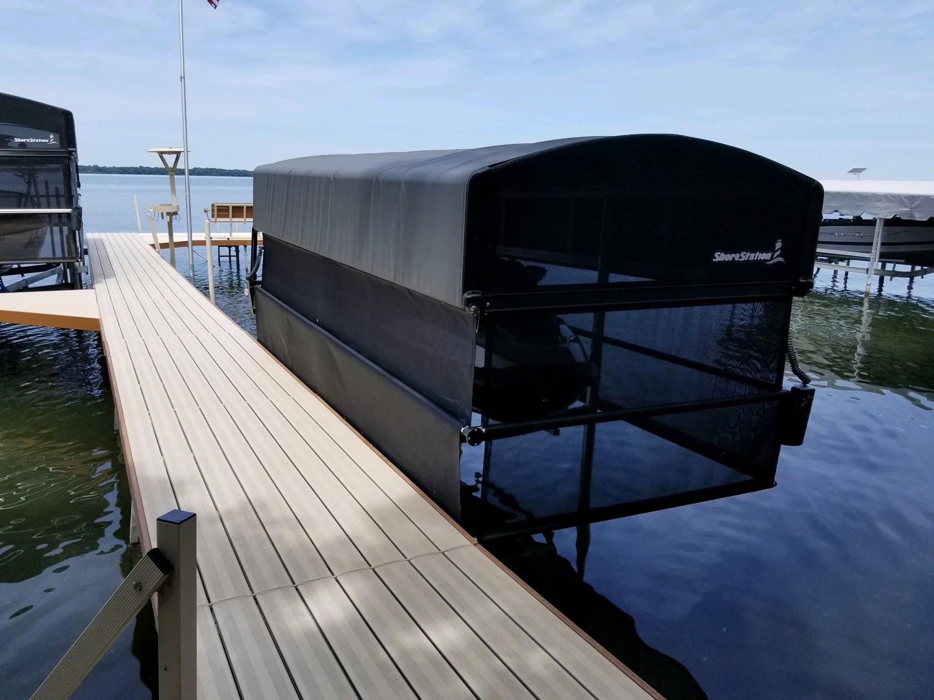 ShoreStation boat lift with a canopy enclosure holding a boat alongside an aluminum lake dock