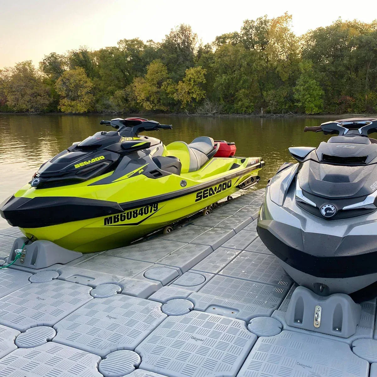 Two Sea-Doo personal watercraft parked on CanDock JetRoll drive-on ports beside a floating dock