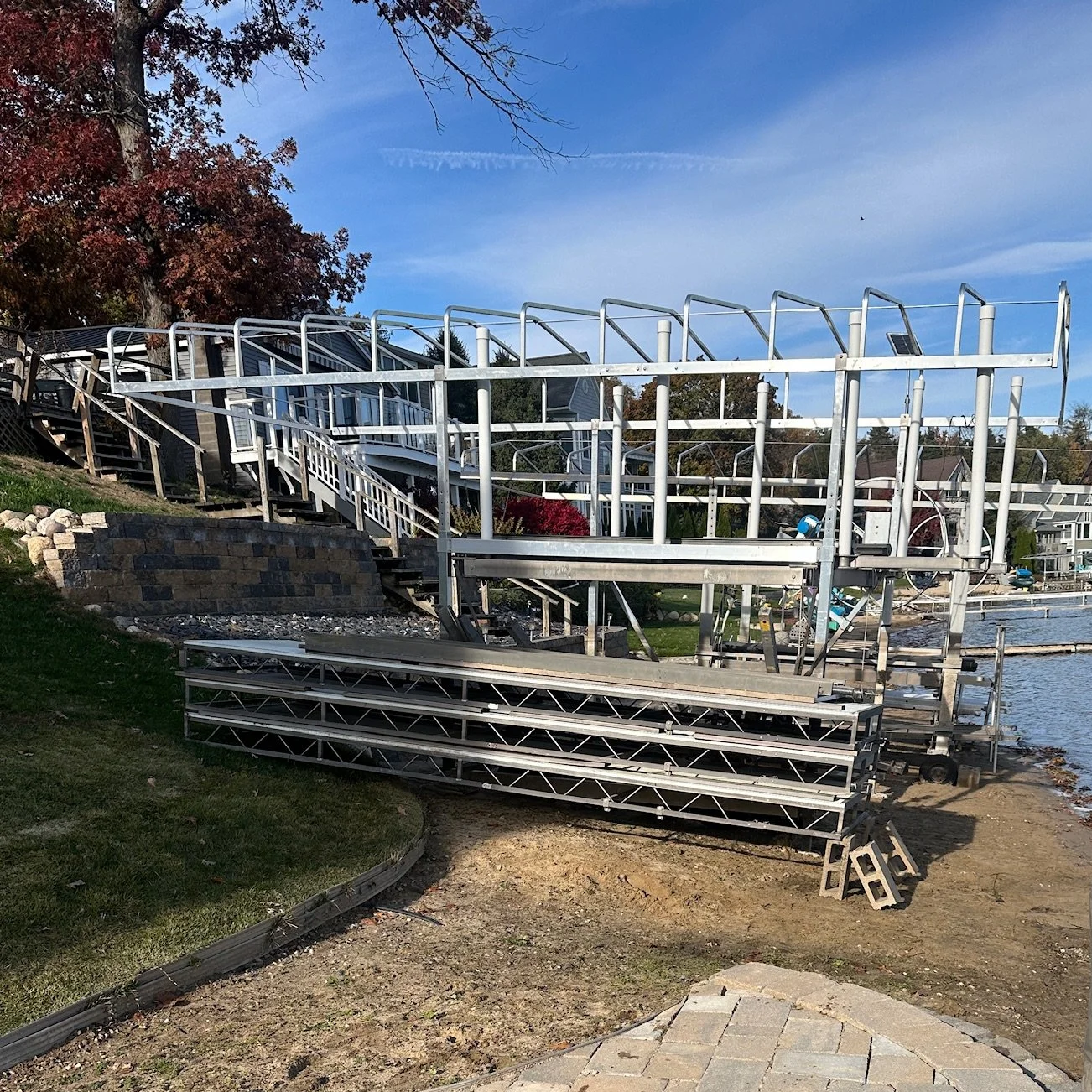 Dock sections stacked on shore with a boat lift pulled out of the water for winter
