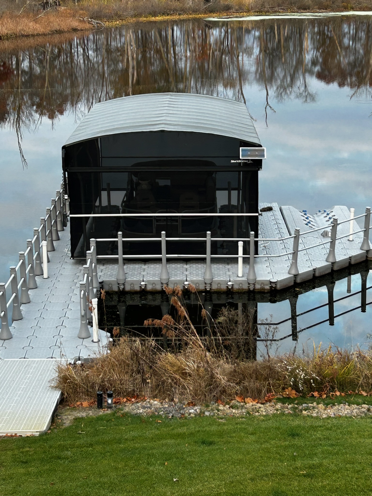 Boat raised on a canopied boat lift at the end of a Beach Bumz dock on a Michigan lake