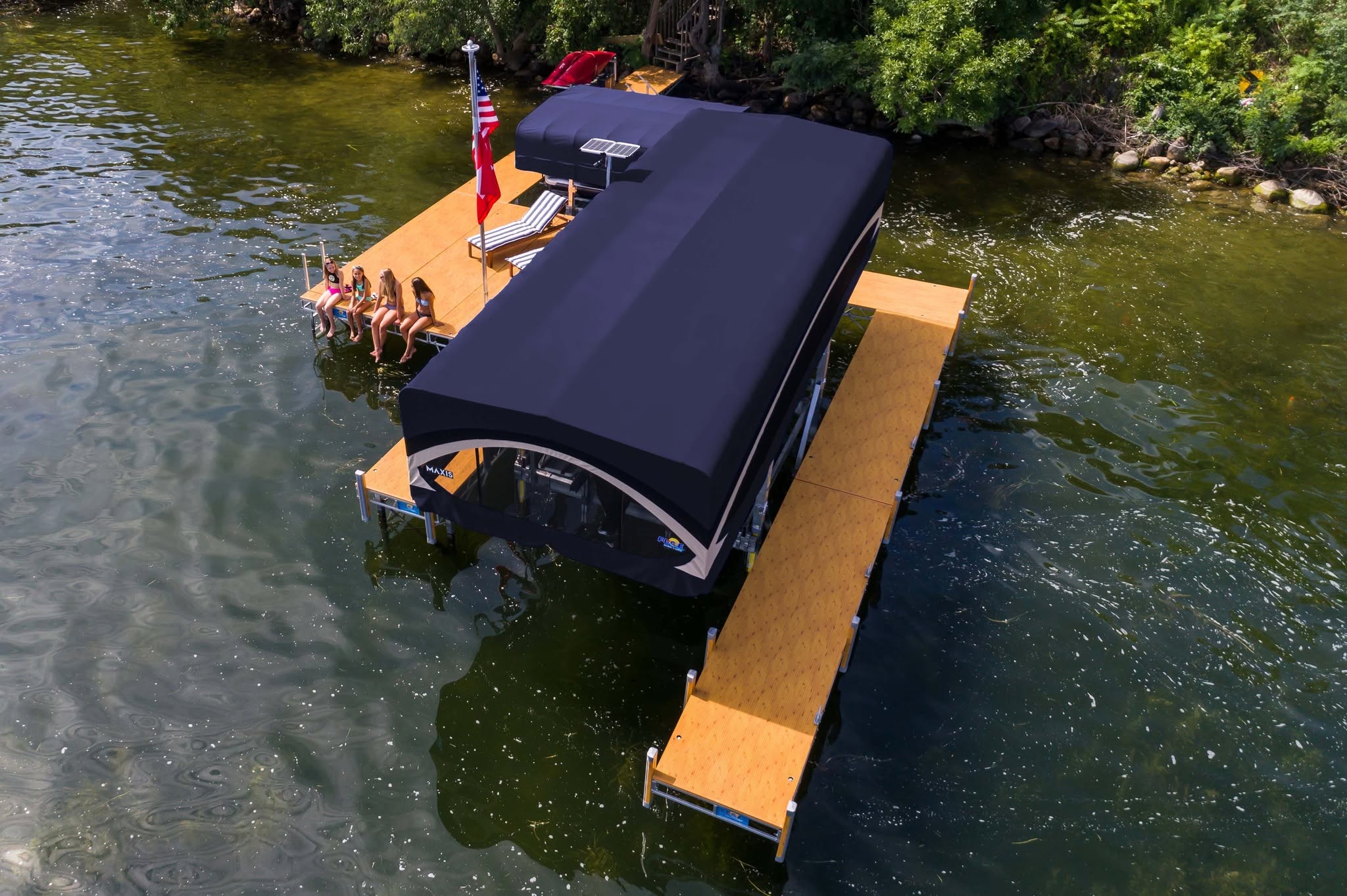 Aerial view of a boat under a FLOE MAXIS canopy on a boat lift beside a wood-tone aluminum dock
