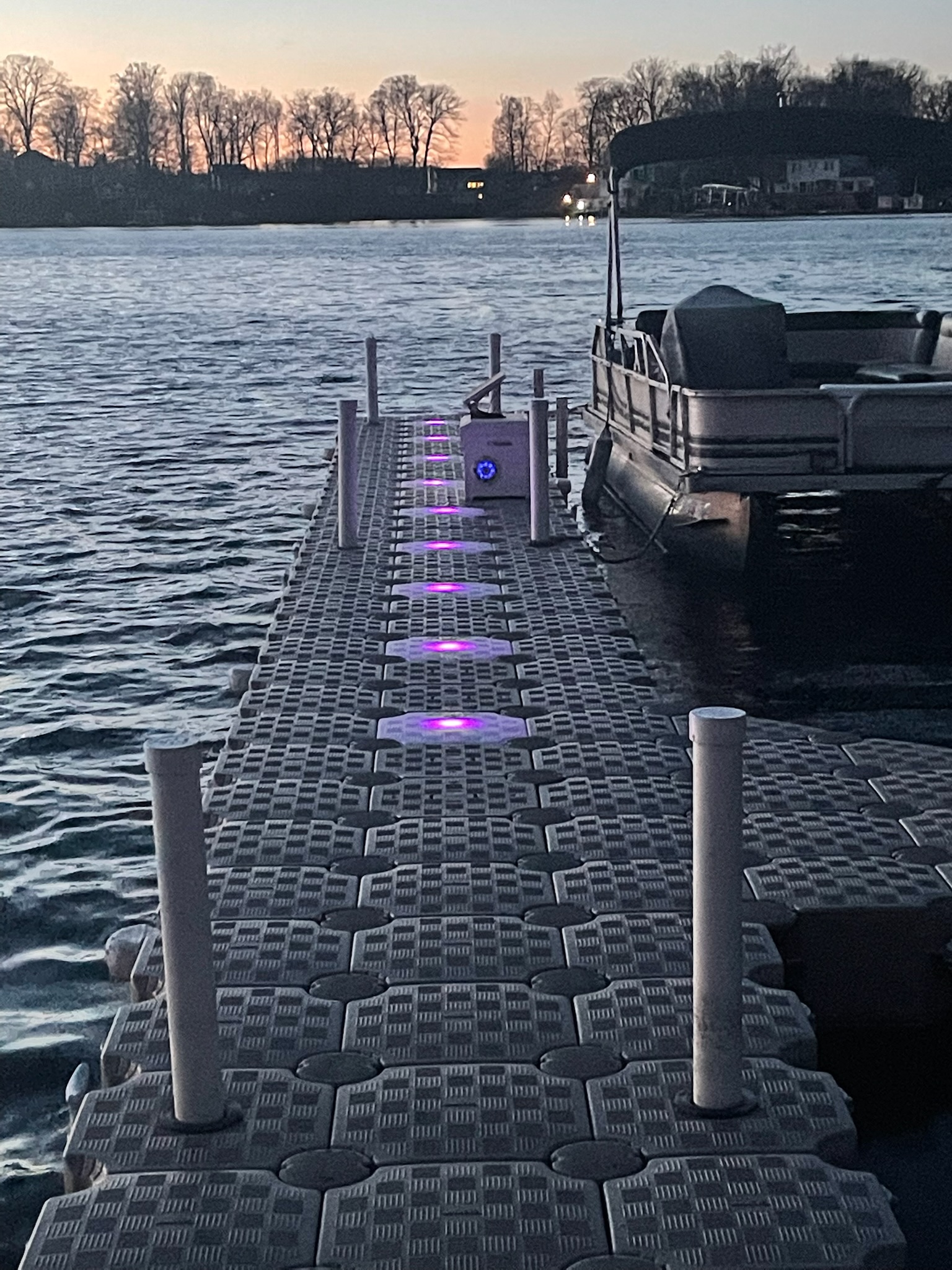 Long CanDock walkway with purple accent lighting extending toward a covered boat at dusk