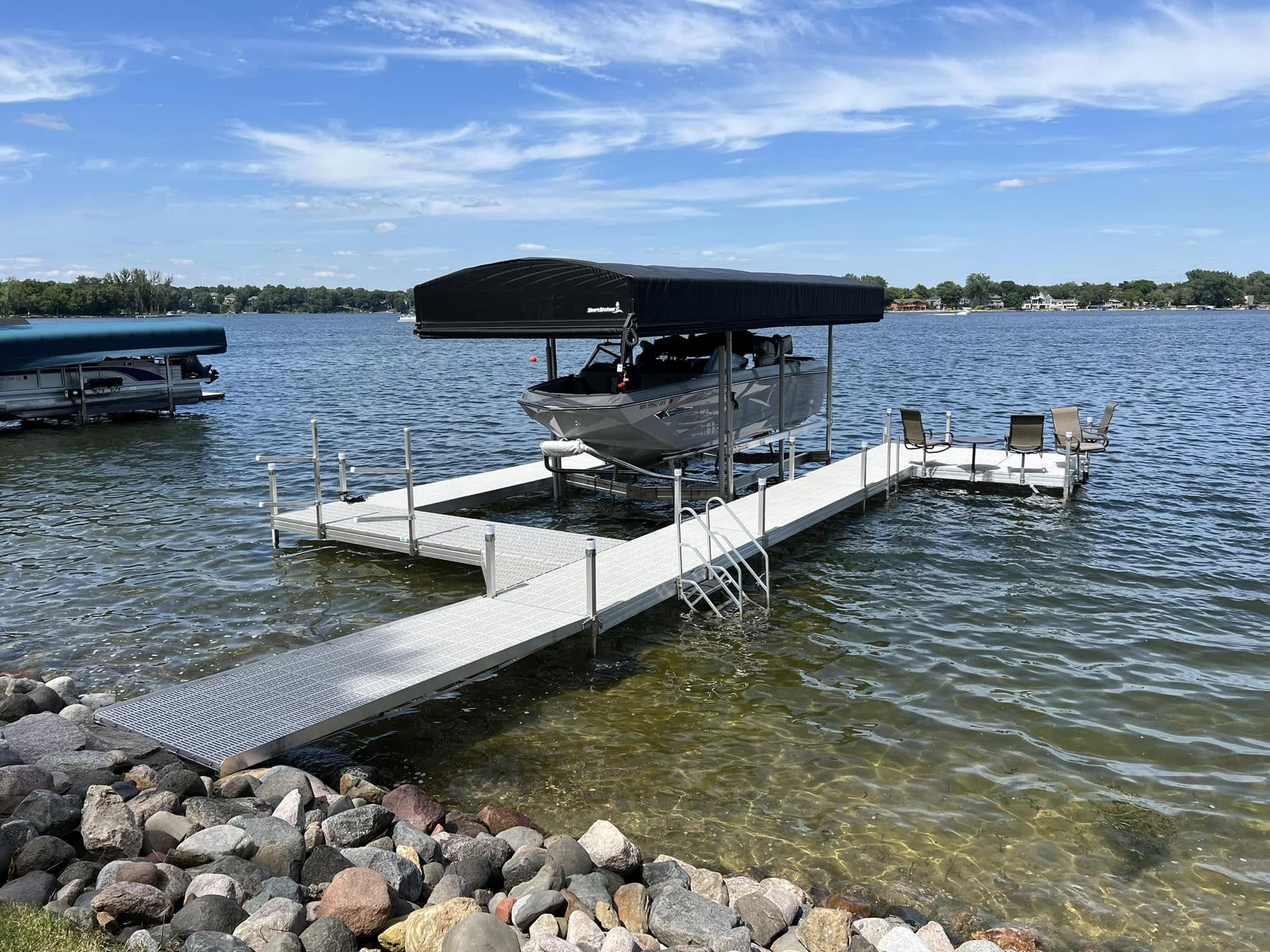 Wake-style boat raised on a canopied boat lift beside a dock on a Michigan lake