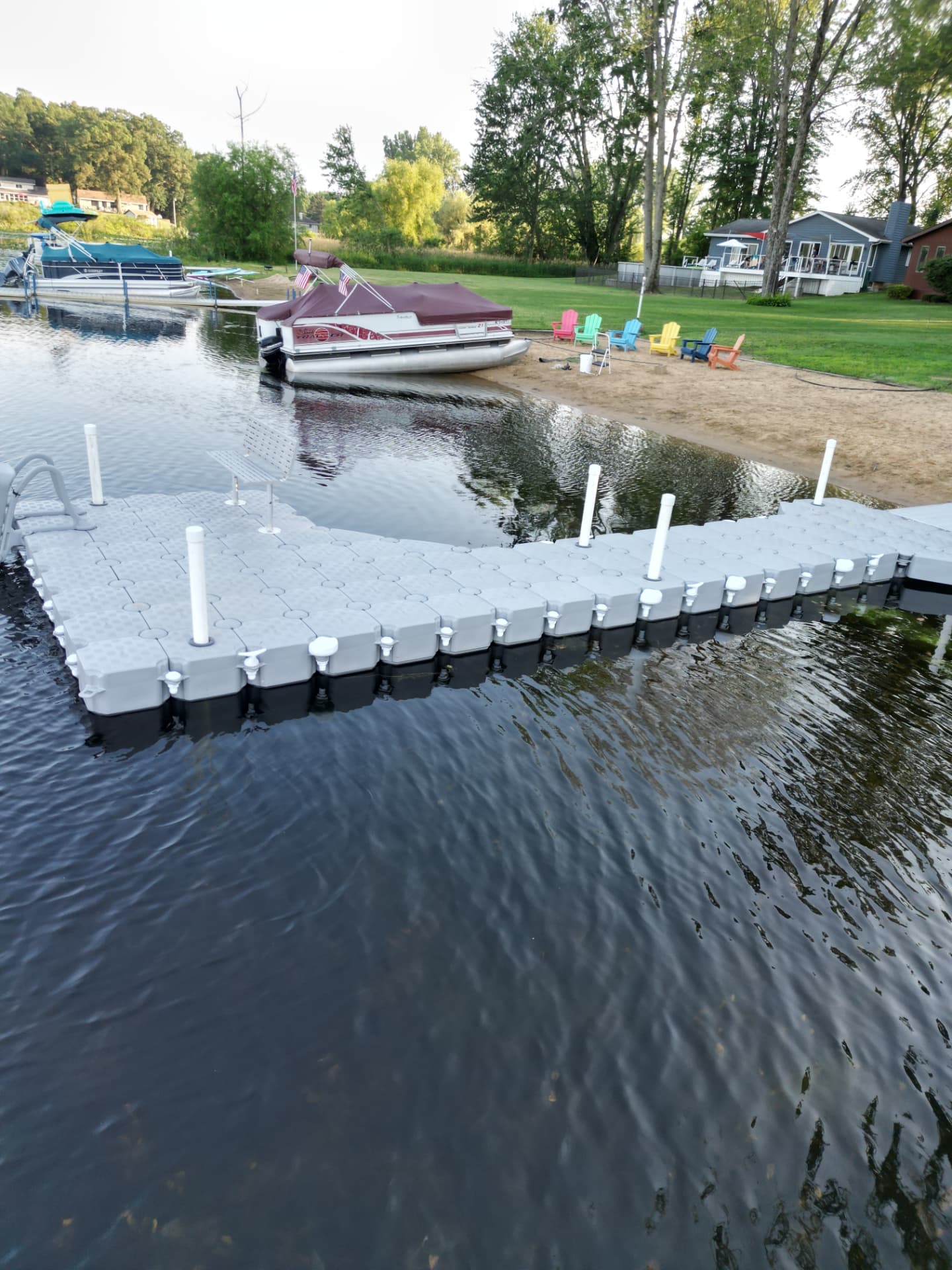 CanDock floating dock beside a sandy Michigan lake beach with a pontoon boat