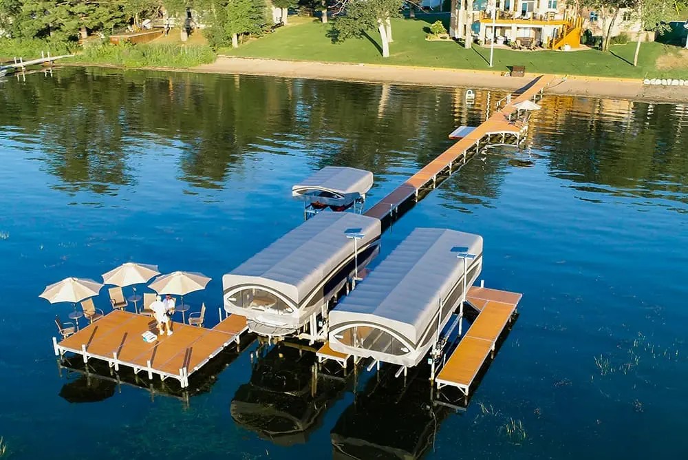 Aerial view of a sectional dock with two covered boat lifts and a shaded lounge platform
