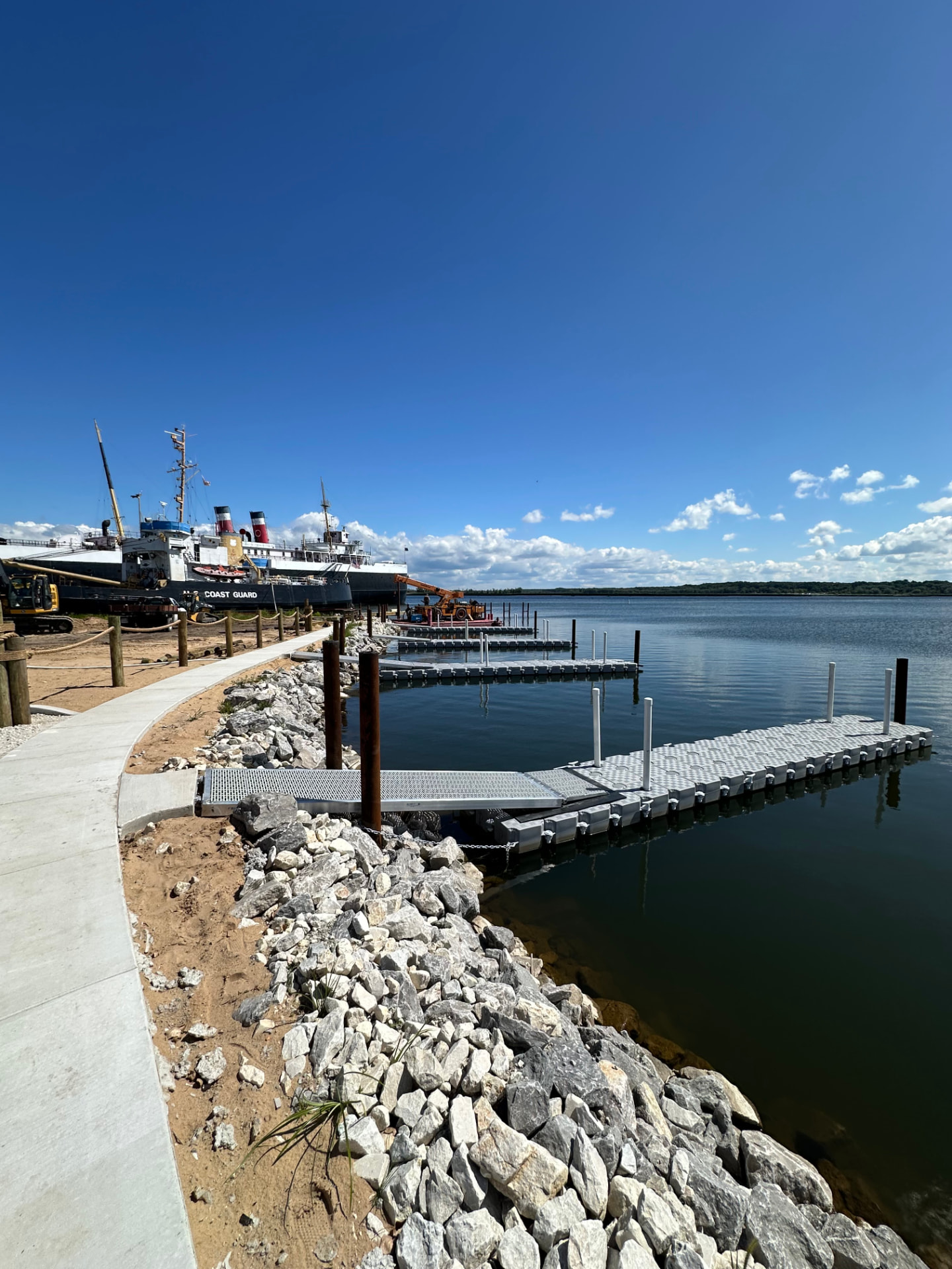 Marina-scale CanDock floating dock system beside a historic Coast Guard vessel and rip-rap shoreline