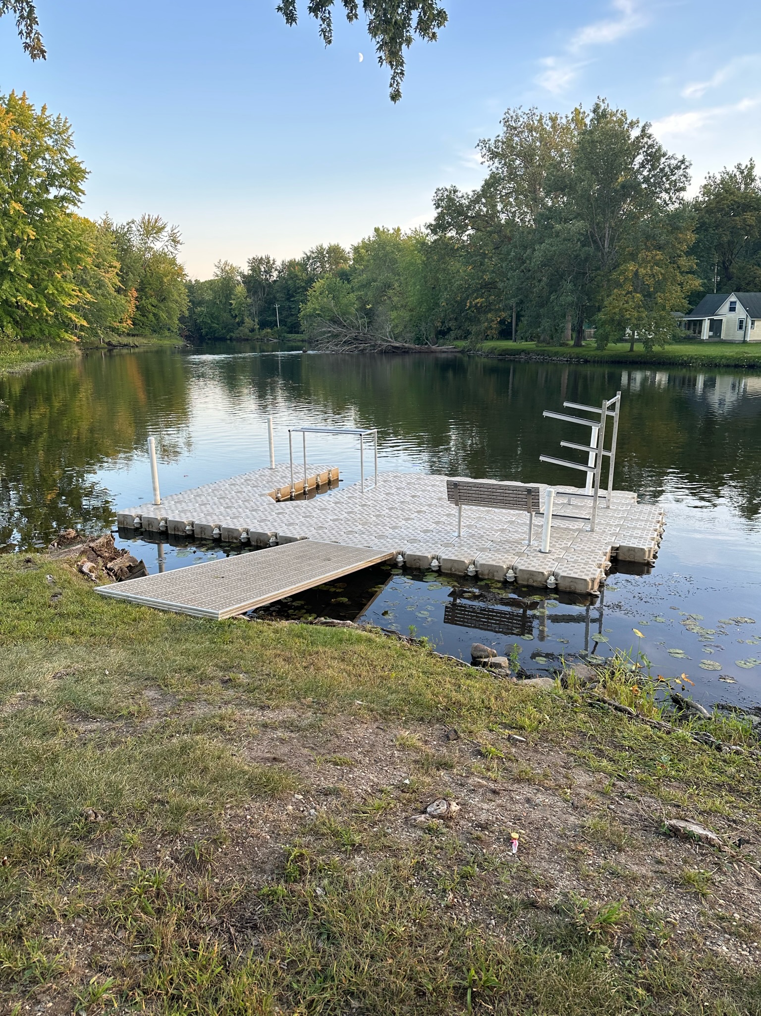 Modular dock platform with a bench and swim ladder on a calm inland lake surrounded by trees