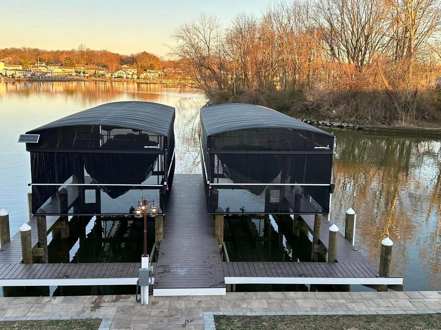 Two covered boat lifts with ShoreScreen side protection installed beside a waterfront dock