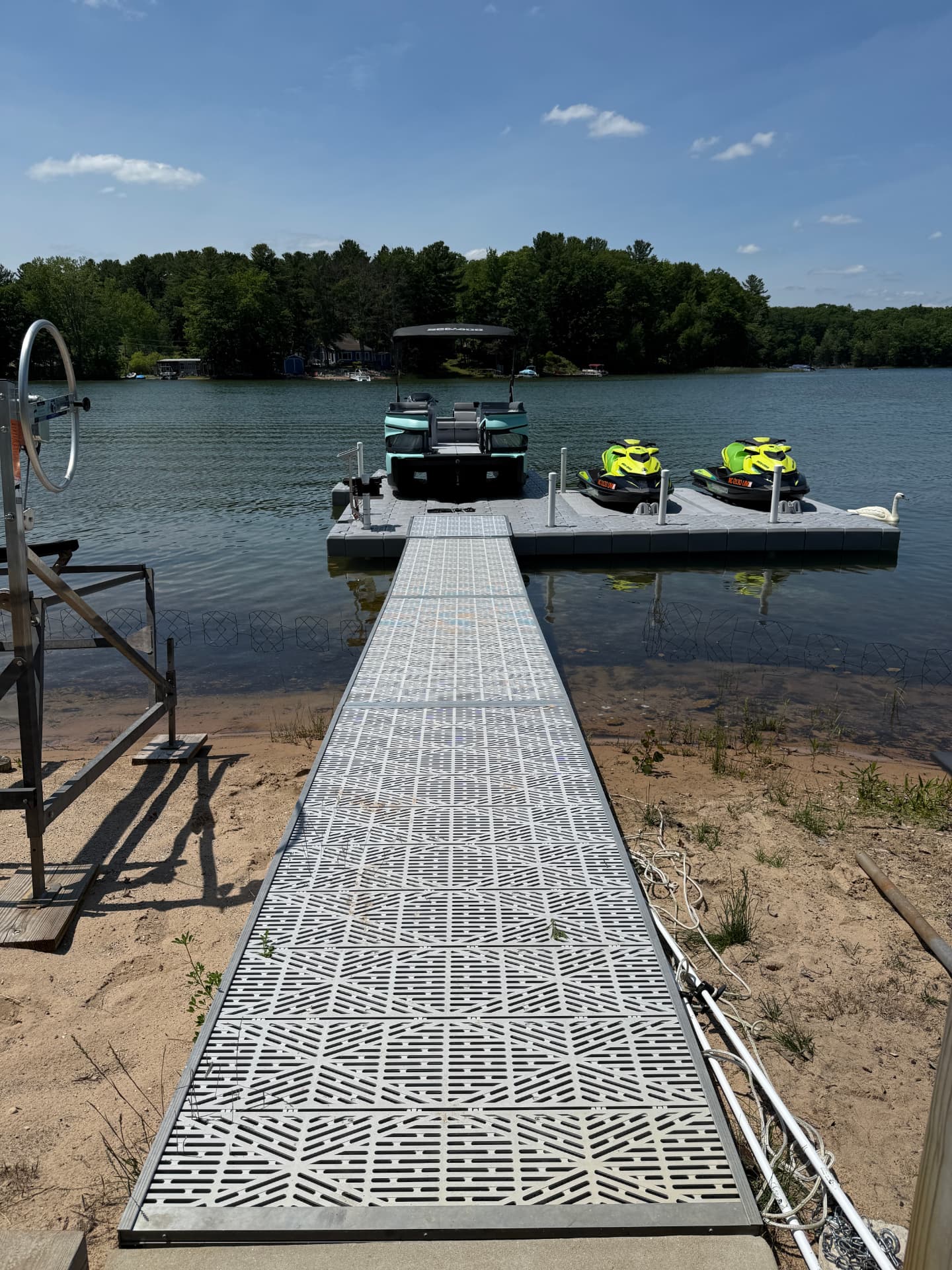 Two personal watercraft parked on a CanDock drive-on floating port beside a pontoon boat